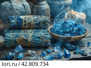 Items that are often associated with meditation, esotericism or relaxation practices. In the center of the frame is a wooden bowl filled with bright blue crystals, likely lapis lazuli stones. To the left of the bowl are bundles of cloth and herbs, similar to resins or smoking sticks, that can be used for space cleansing or aromatherapy. Smoke from the resin floats above the bowl, giving the scene a mystical atmosphere. The background is made up of antique vases and natural wood, which emphasizes the naturalness and traditionality of the scene. Стоковое AI-изображение, AI-художник Анна Кривицкая / Фотобанк Лори