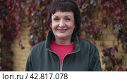 Portrait of happy mature woman buttoning zipper on gray leather jacket smiling outdoors. Стоковое видео, видеограф EStarodubov / Фотобанк Лори