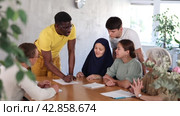 Adult African American male tutor conducting lesson for group of interested adult people of different nationalities sitting around table in classroom in foreign language school. Стоковое видео, видеограф Яков Филимонов / Фотобанк Лори