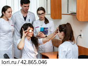 Женщина врач-офтальмолог смотрит глаз пациентки (2022 год). Редакционное фото, фотограф Elena Kotova / Фотобанк Лори