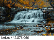 Picturesque waterfall in the forest in autumn. The water rushes forcefully over multi-level rocky rapids, creating a striking contrast with the warm colors of the autumn foliage surrounding the pond. The leaves of the trees, painted in golden and copper tones, glow against the background of dark blue water and stones, which adds peace and harmony to the scene. Стоковое AI-изображение, AI-художник Анна Кривицкая / Фотобанк Лори
