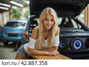 A beautiful blonde girl at an auto sound competition. Car music. Subwoofers, amplifiers, acoustics. Car audio system. Стоковое AI-изображение, AI-художник Александр Поташев / Фотобанк Лори
