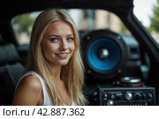A beautiful blonde girl at an auto sound competition. Car music. Subwoofers, amplifiers, acoustics. Car audio system. Стоковое AI-изображение, AI-художник Александр Поташев / Фотобанк Лори