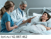 Man lying in bed and woman talking to doctor. Стоковое AI-изображение, AI-художник Ярославский Максим / Фотобанк Лори