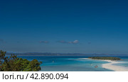 A delightful tropical landscape. A winding sandbar leads to a small island covered with green vegetation. The boats are anchored in the aquamarine ocean. Mountains against the blue sky in the distance. Стоковое фото, фотограф Вера Ивановна Кубарева / Фотобанк Лори