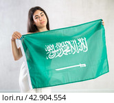 Happy young woman with flag of Saudi Arabia against unicoloured background. Стоковое фото, фотограф Яков Филимонов / Фотобанк Лори