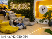 Посетители отдыхают на стенде компании "Яндекс" в павильоне выставки во время проведения Международной выставки-форума "Россия" на территории выставочного комплекса ВДНХ в городе Москве, Россия (2024 год). Редакционное фото, фотограф Николай Винокуров / Фотобанк Лори