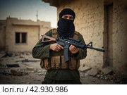 Terrorists with a machine gun on the background of military operations.Isis is a terrorist. Стоковое AI-изображение, AI-художник Александр Поташев / Фотобанк Лори