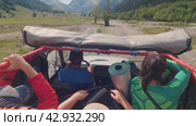 SUV with tourists driving on gravel stony in the mountains. First-person view of saloon with people and driver. Ahead are high mountains with snow on the tops. Off-road journey. Russia June 2, 2023. Редакционное видео, видеограф Воловодов Владимир / Фотобанк Лори