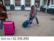 Люди идут с чемоданами к Белорусскому вокзалу на площади Тверской заставы в центре города Москвы, Россия (2024 год). Редакционное фото, фотограф Николай Винокуров / Фотобанк Лори