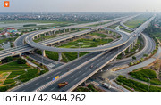 A birdseye view of a bustling highway interchange in a metropolitan area. Стоковое AI-изображение, AI-художник Юрий Поздников / Фотобанк Лори
