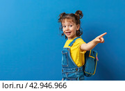 Portrait of a happy little girl 5-6 years old on a blue background, a separate place for the text. A hand gesture. Стоковое AI-изображение, AI-художник Ярославский Максим / Фотобанк Лори