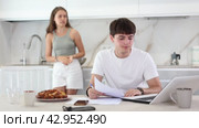 Upset young man sitting at computer with her back to her wife disputing with her in the kitchen. Стоковое видео, видеограф Яков Филимонов / Фотобанк Лори