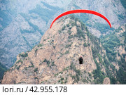 red paraglider flies against the background of mountains, rear view. Стоковое фото, фотограф Александр Довянский / Фотобанк Лори