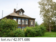 A street in the town of Tutaev, Russia, with single-storey wooden houses, bushes and tree in the evening (2023 год). Стоковое фото, фотограф Сергей Фролов / Фотобанк Лори
