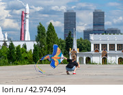 Москва, ВДНХ девочка играет на площадке запуская воздушного змея в виде жар-птицы (2022 год). Редакционное фото, фотограф Валерий Леонидович / Фотобанк Лори