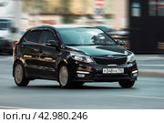 Front side view of black car Kia Rio Third generation. Fast moving Kia K2 hatchback on the street. Vehicle driving along the street in city with blurred background. Редакционное фото, фотограф Константин Григорьев / Фотобанк Лори