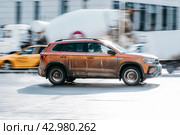 Fast moving volkswagen taos on the city road. Orange SUV driving on motorway. Dirty auto in fast motion with blurred background. Редакционное фото, фотограф Константин Григорьев / Фотобанк Лори