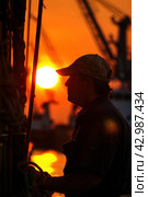 Man in hat on boat at sunset, amber sky, shades of orange, heat dissipating. Стоковое AI-изображение, AI-художник Юрий Поздников / Фотобанк Лори