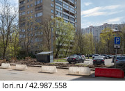 Укладка бордюрного камня на улице Академика Комарова в Москве. Зона земляных работ огорожена с помощью белых и красных пластиковых блоков (2024 год). Редакционное фото, фотограф Наталья Николаева / Фотобанк Лори