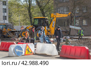 Рабочие меняют бордюрный камень на улице Академика Комарова в Москве. Прямо по огороженному для ремонтных работ тротуару рядом с работающим экскаватором идут люди с детской коляской. Маленький мальчик едет на велосипеде. Нарушение техники безопасности проведения работ (2024 год). Редакционное фото, фотограф Наталья Николаева / Фотобанк Лори
