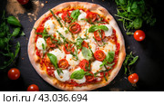 Delicious aromatic pizza with gooey cheese, salami, pepperoni, and basil, next to the ingredients on a dark table surface. Стоковое AI-изображение, AI-художник ALLA YURTAYEVA / Фотобанк Лори