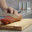 Man cuts thin slices of sausage on a wooden board with a knife. Close-up of the hands. Стоковое видео, видеограф EStarodubov / Фотобанк Лори