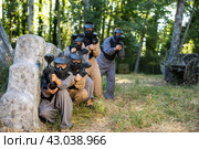 Paintball players of one team in camouflages and masks aiming with gun in shootout. Стоковое фото, фотограф Яков Филимонов / Фотобанк Лори