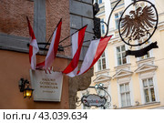 Флаги и герб Австрии на фасаде дома с готической жилой башней в Вене (2023 год). Редакционное фото, фотограф V.Ivantsov / Фотобанк Лори