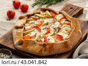 Homemade savory galette with vegetables, wholegrain pie with tomatoes, zucchini, side view. Стоковое фото, фотограф Natalia Gdovskaia / Фотобанк Лори