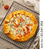 Homemade savory galette with vegetables, wheat pie with tomatoes, zucchini, vertical. Стоковое фото, фотограф Natalia Gdovskaia / Фотобанк Лори