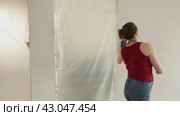 A woman with brown hair paints the walls white and inspects them for defects. Стоковое видео, видеограф Ольга Коваленко / Фотобанк Лори