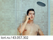 Young white man talks by smartphone in shower stall. Стоковое фото, фотограф Владимир Григорьев / Фотобанк Лори