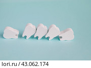 Концепция кривых и неровных зубов. Ряд игрушечных деревянных зубов на голубом фоне. Проблемный зубной ряд. Стоковое фото, фотограф Дорощенко Элла / Фотобанк Лори