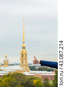 Мужская рука показывает жест - это хорошо, это круто, большой палец вверх. На фоне исторических достопримечательностей города Санкт-Петербурга, Россия. Петропавловская крепость и собор. Стоковое фото, фотограф Андрей Степанов / Фотобанк Лори