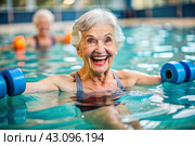 An elderly woman swims and does water aerobics in a heated pool, a happy and smiling retired woman. Recreational water sports. Стоковое AI-изображение, AI-художник Photojuli / Фотобанк Лори