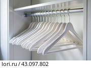 Close-up of white hangers on a white closet. The concept of order and storage in the house. Стоковое AI-изображение, AI-художник Photojuli / Фотобанк Лори