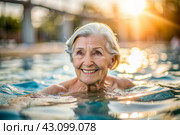 An elderly woman swims and does water aerobics in a heated pool, a happy and smiling retired woman. Recreational water sports. Стоковое AI-изображение, AI-художник Photojuli / Фотобанк Лори