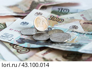 Блестящая монета номиналом один рубль ₽ на фоне бумажных десяти-,  пятидесяти-  и сторублевых купюр и нескольких монет. Крупный план. Выборочный фокус.  Russian rubles. Стоковое фото, фотограф Лариса Гордеева / Фотобанк Лори