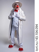 An elderly laughing clown in a white coat, hat and large red patent leather clown boots. Walking stick in hand. Стоковое фото, фотограф Сергей Пристяжнюк (Serg Zastavkin) / Фотобанк Лори