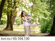 Woman holds little child and talks by cell phone outdoors. Стоковое фото, фотограф Владимир Григорьев / Фотобанк Лори