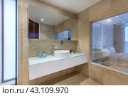 Laconic design of the hotel bathroom with beige tiles on the walls, a large mirror and a sink. Стоковое фото, фотограф Алексей Климкин / Фотобанк Лори