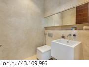 The laconic interior of the hotel bathroom is lined with beige tiles, a large mirror and a sink. Стоковое фото, фотограф Алексей Климкин / Фотобанк Лори