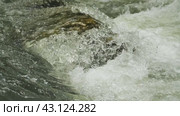 Крупный план воды, мчащейся вокруг камня в реке. Вода белая и пенистая, что свидетельствует о турбулентном потоке. На скале есть темные и светлые участки, возможно, из-за минералов, лишайника или влаги. Стоковое видео, видеограф Воловодов Владимир / Фотобанк Лори
