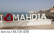 I Love Mahdia sign standing on sun-drenched seafront in Tunisian coastal city with Mediterranean Sea in background. Стоковое видео, видеограф Яков Филимонов / Фотобанк Лори