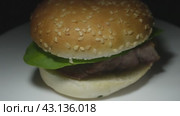 A fresh burger bun with a piece of fried pork and greens on a white plate. Стоковое видео, видеограф Ярославский Максим / Фотобанк Лори