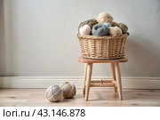 Balls of yarn in a wicker basket in white and beige tones. Needlework, textiles, knitting. Winter season, small business, handmade clothes. Стоковое AI-изображение, AI-художник Photojuli / Фотобанк Лори