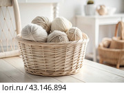Balls of yarn in a wicker basket in white and beige tones. Needlework, textiles, knitting. Winter season, small business, handmade clothes. Стоковое AI-изображение, AI-художник Photojuli / Фотобанк Лори