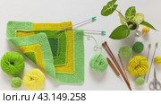 Video of hand knitting square pattern using 10-stitch method from yarn of green and yellow wool on white background. Spring needlework. DIY concept. Flat lay, close-up, top view. Стоковое видео, видеограф Виктория Катьянова / Фотобанк Лори