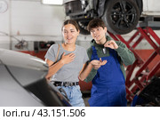 Young mechanic handing over remote key to female customer. Стоковое фото, фотограф Яков Филимонов / Фотобанк Лори